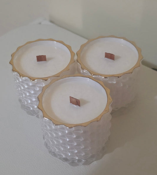 Three Serenus Spa Luxe cocosoy candles in white geometric jars with gold rims and wooden wicks.