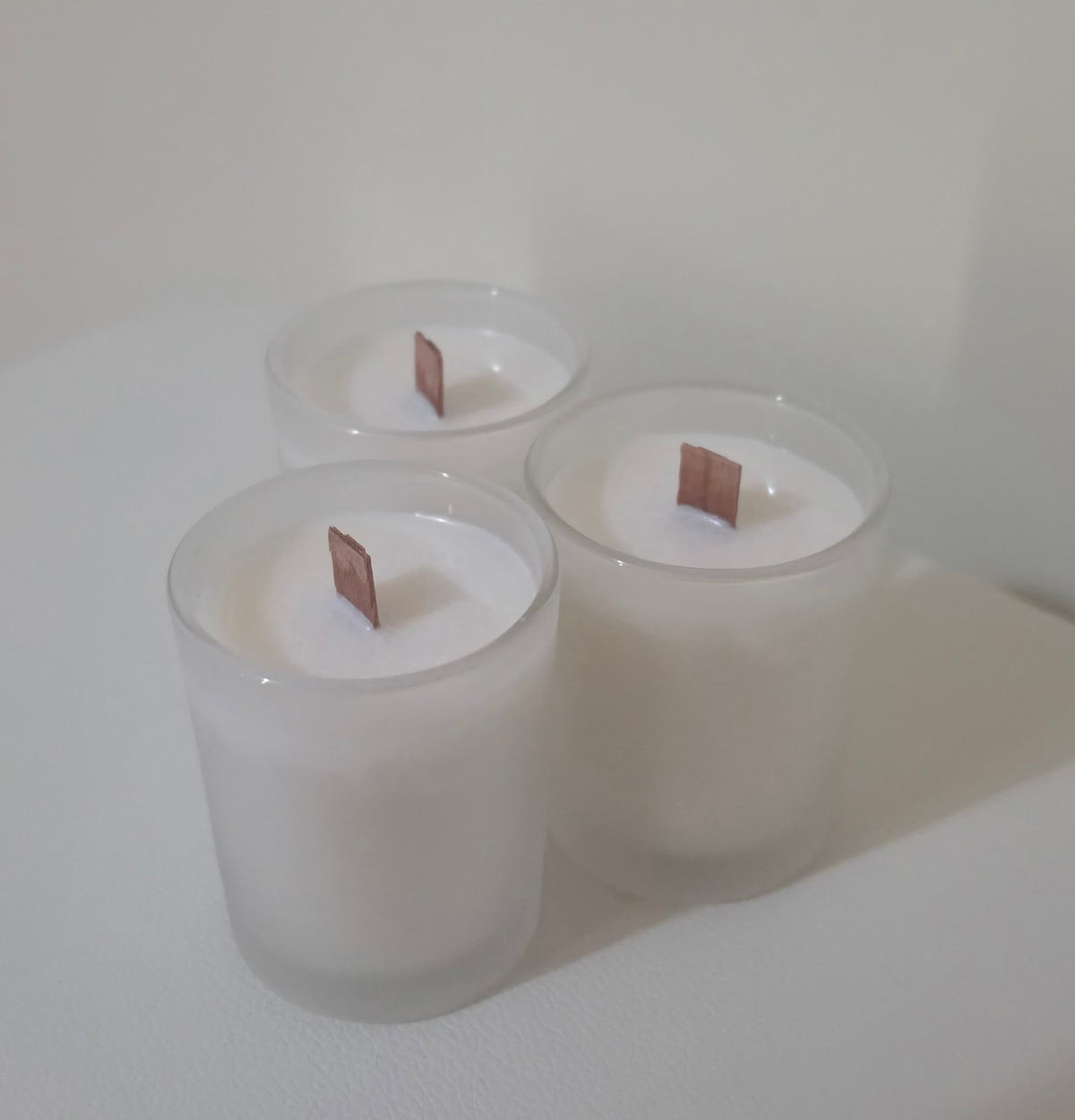 Three Serenus Spa cocosoy candles in white frosted glass jars with wooden wicks, arranged as a Spa gift pack.
